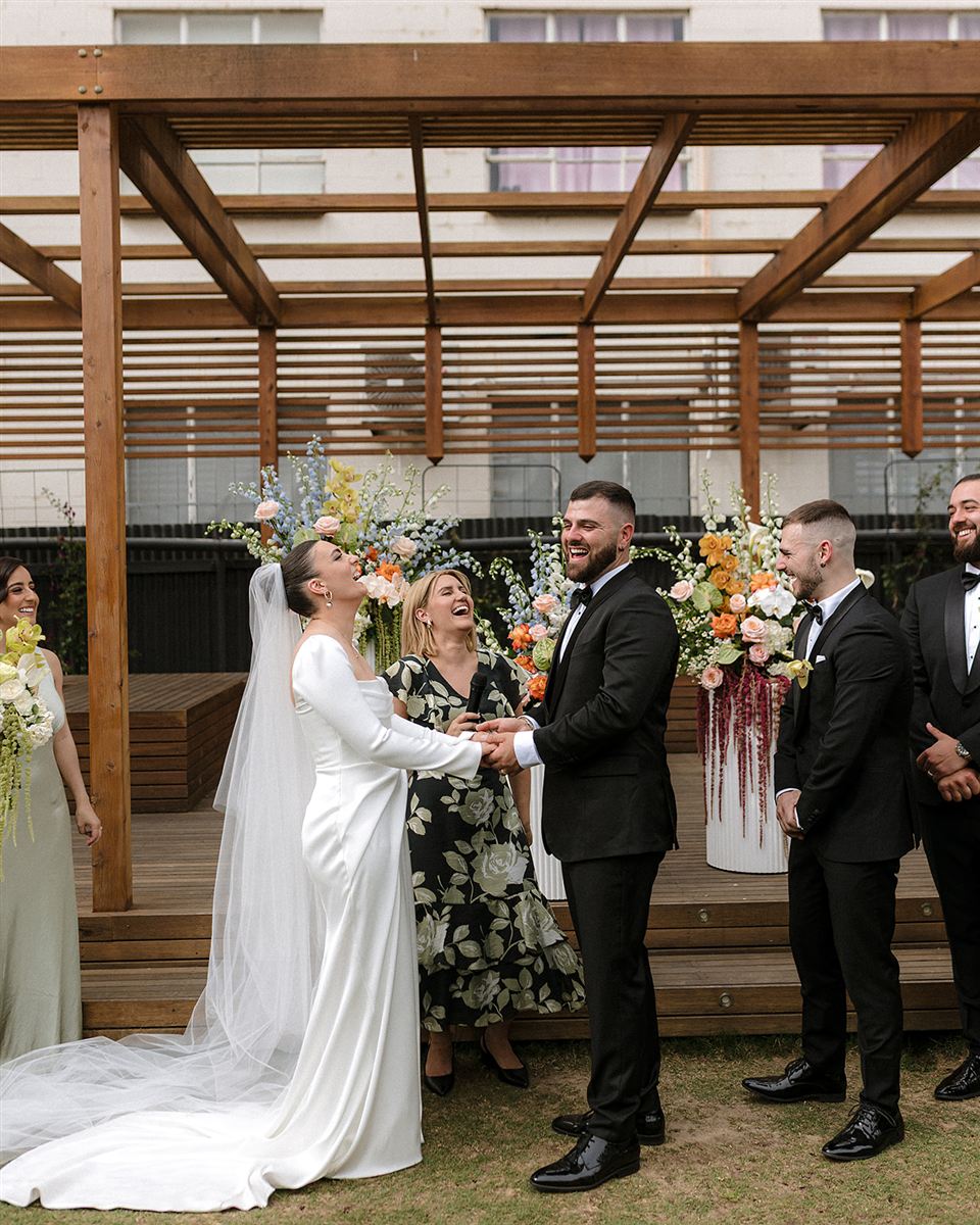 Renée Melizza officiating as Lidia, Daniel and their wedding party burst into laughter during the garden ceremony